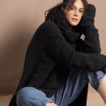 A woman wears an oversized 100% cashmere sweater in black