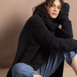 A woman wears an oversized 100% cashmere sweater in black