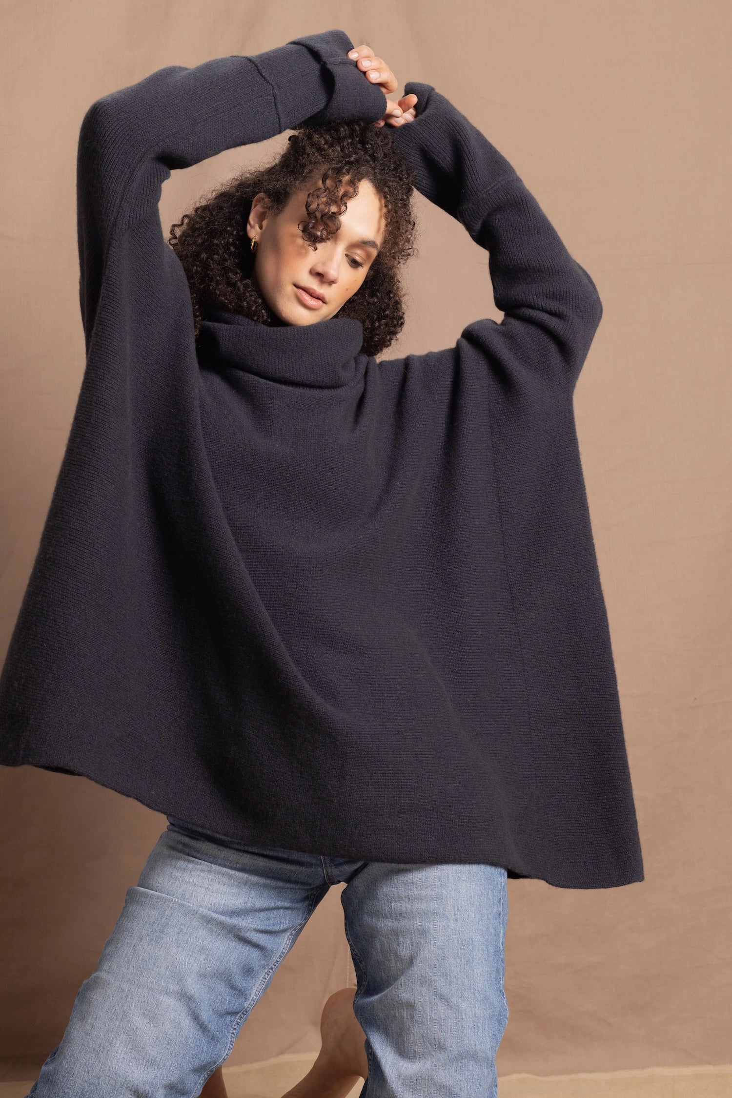 A woman wears an oversized cashmere sweater in a grey blue colour with jeans