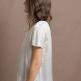 A woman wears a 100% silk v-neck t-shirt in white with a pair of jeans
