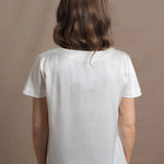 A woman wears a 100% silk v-neck t-shirt in white with a pair of jeans