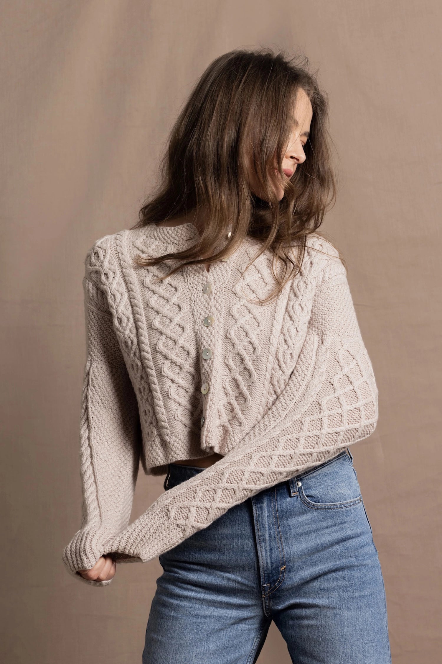 A lady wears a pure 100% cashmere Irish aran sweater cardigan in soft pink