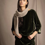 Woman wearing a beige cashmere scarf with gold metallic lurex thread over green silk velvet outfit