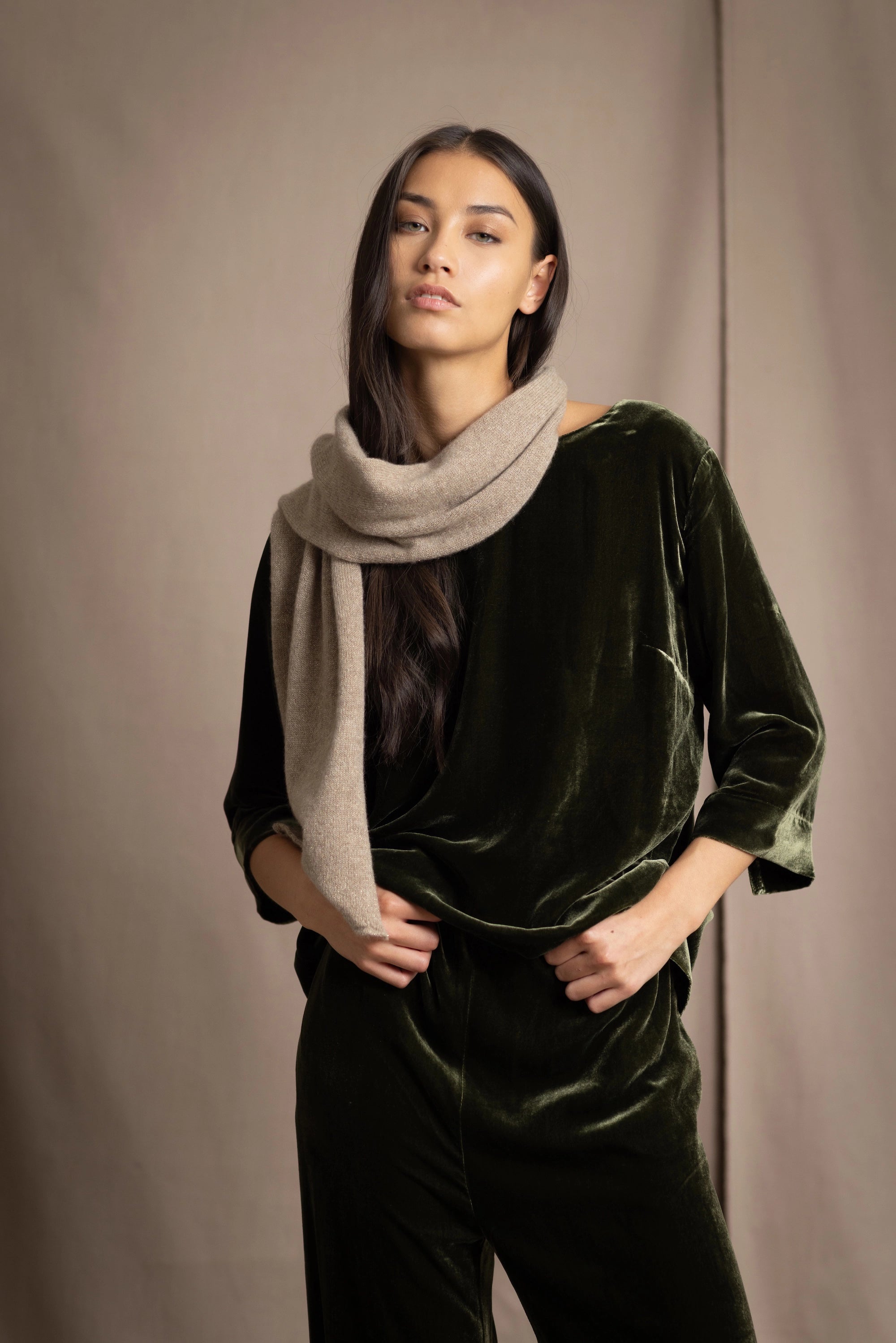 Woman wearing a beige cashmere scarf with gold metallic lurex thread over green silk velvet outfit