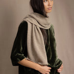 Woman wearing a beige cashmere scarf with gold metallic lurex thread over green silk velvet outfit