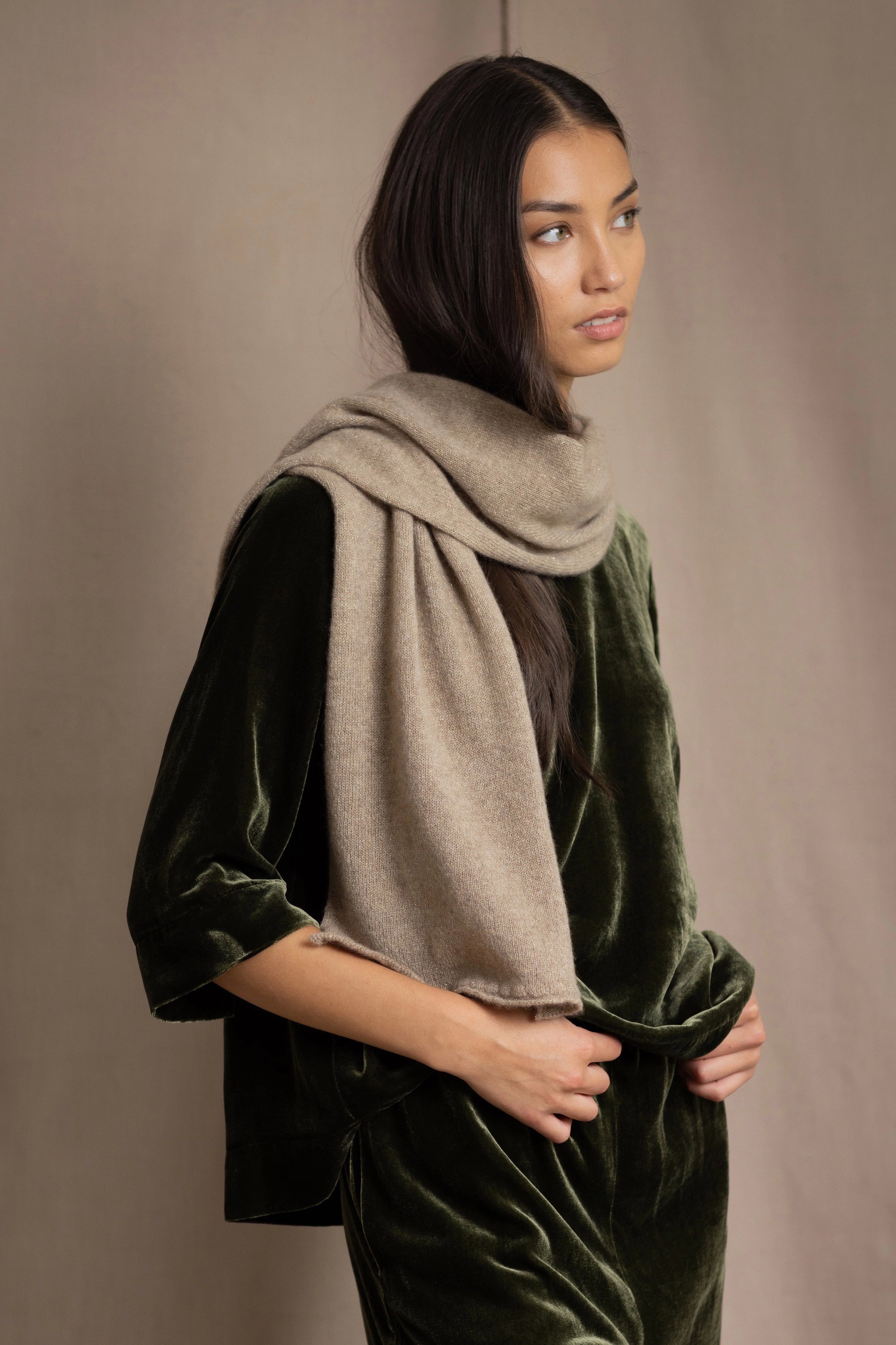 Woman wearing a beige cashmere scarf with gold metallic lurex thread over green silk velvet outfit