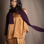 a woman wearing a cashmere scarf in dark purple over bronze silk clothing