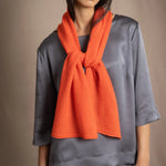 woman wearing a bright orange cashmere scarf over pewter grey silk clothing