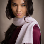 a woman wears a small cashmere scarf in pale pink worn over burgundy silk clothing