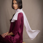 a woman wears a small cashmere scarf in pale pink worn over burgundy silk clothing