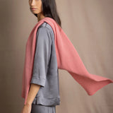 a woman wearing a cashmere scarf in dusty rose pink with a cashmere beanie hat over grey pewter silk clothing