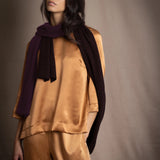 a woman wearing a cashmere scarf in dark brown over bronze silk clothing