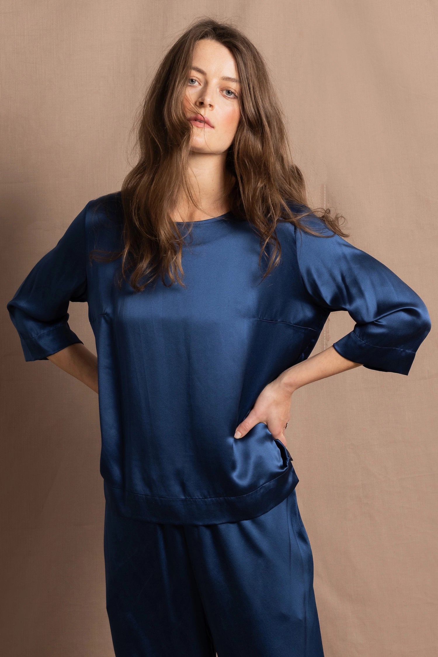 A lady wears a pure silk 3/4 sleeve blouse in teal with matching trousers