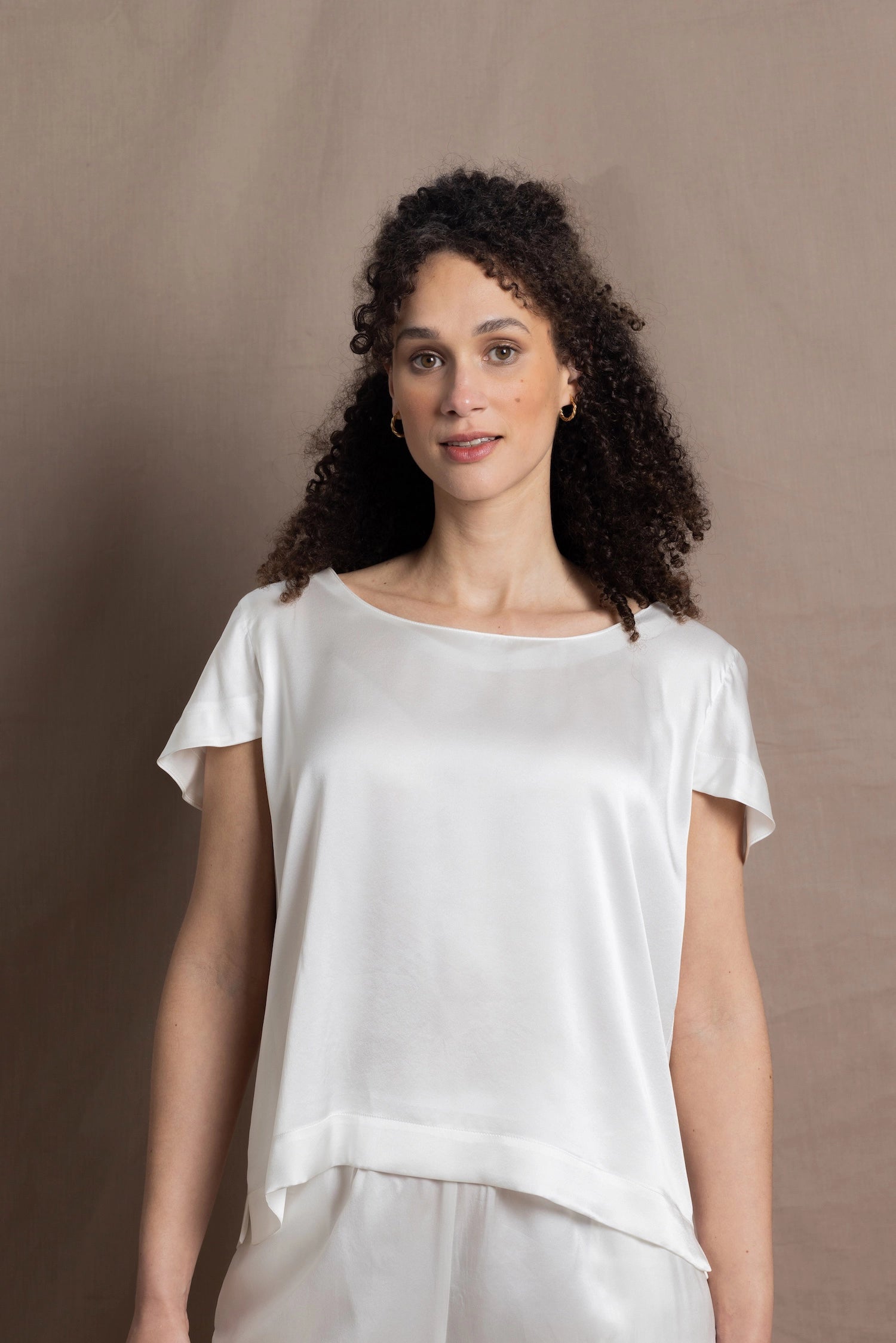 A lady wears a crew neck silk tshirt in white with butterfly sleeves