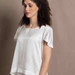 A lady wears a crew neck silk tshirt in white with butterfly sleeves