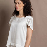 A lady wears a crew neck silk tshirt in white with butterfly sleeves
