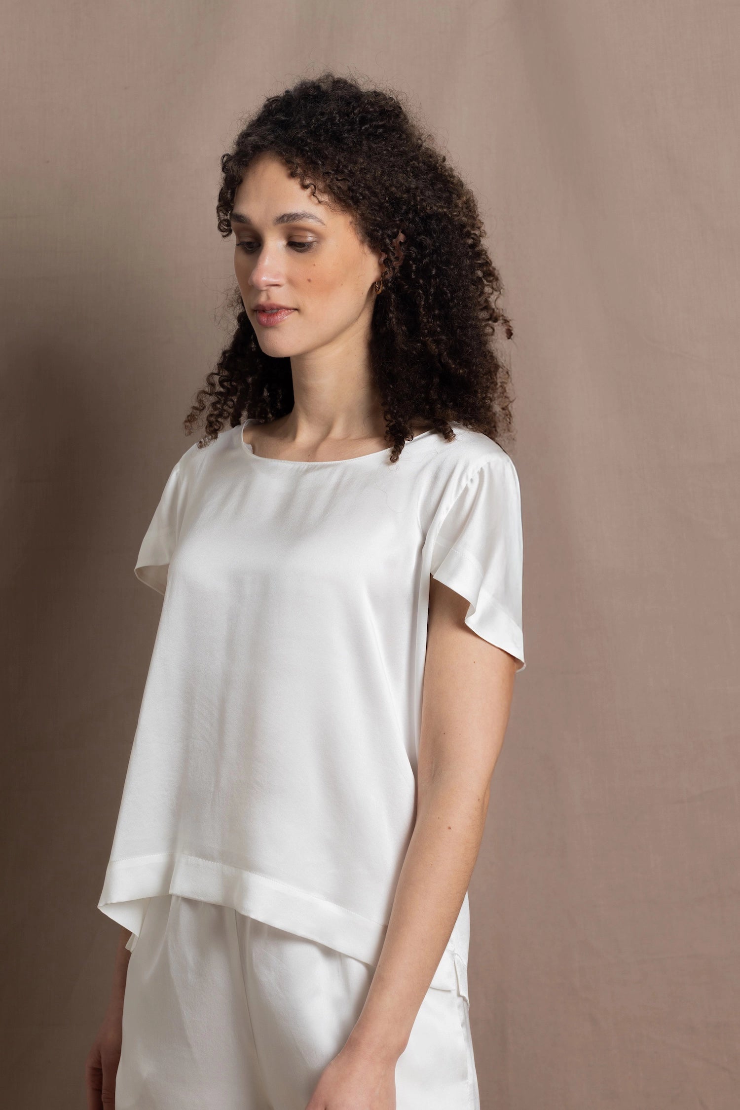 A lady wears a crew neck silk tshirt in white with butterfly sleeves