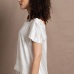 A lady wears a crew neck silk tshirt in white with butterfly sleeves