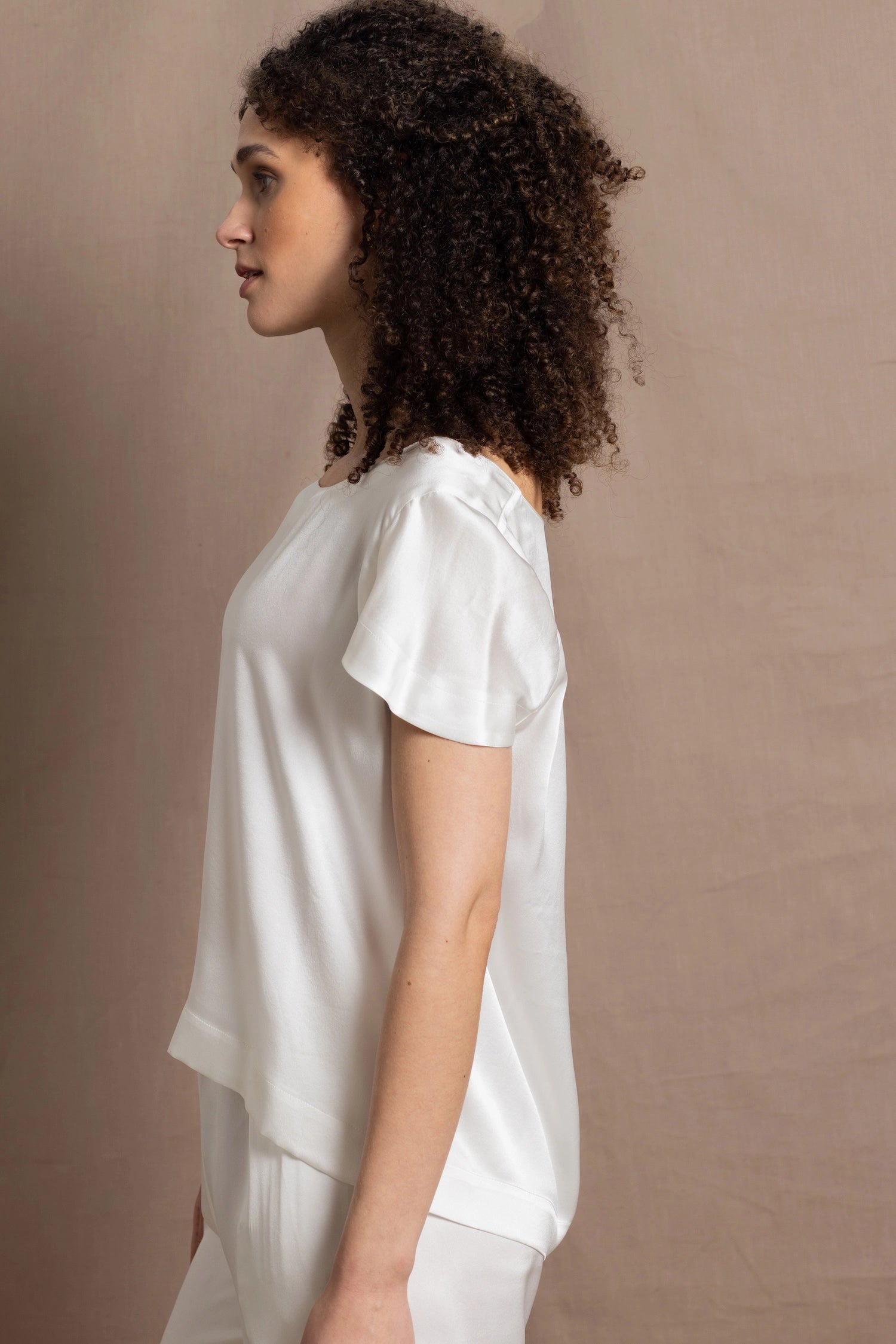 A lady wears a crew neck silk tshirt in white with butterfly sleeves
