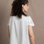 A lady wears a crew neck silk tshirt in white with butterfly sleeves