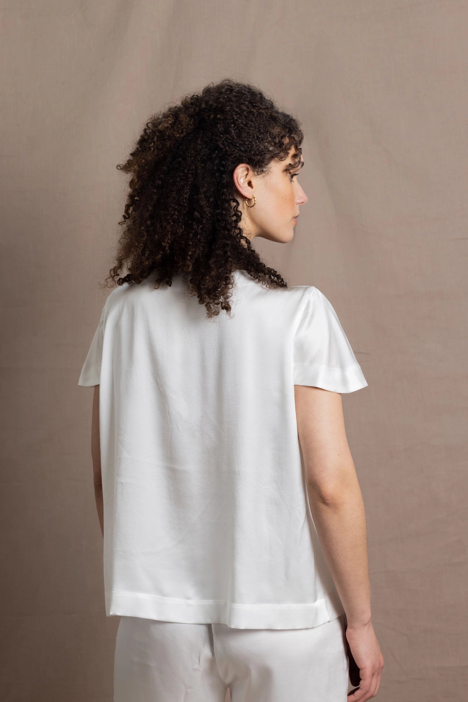 A lady wears a crew neck silk tshirt in white with butterfly sleeves