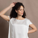 A lady wears a crew neck silk tshirt in white with butterfly sleeves