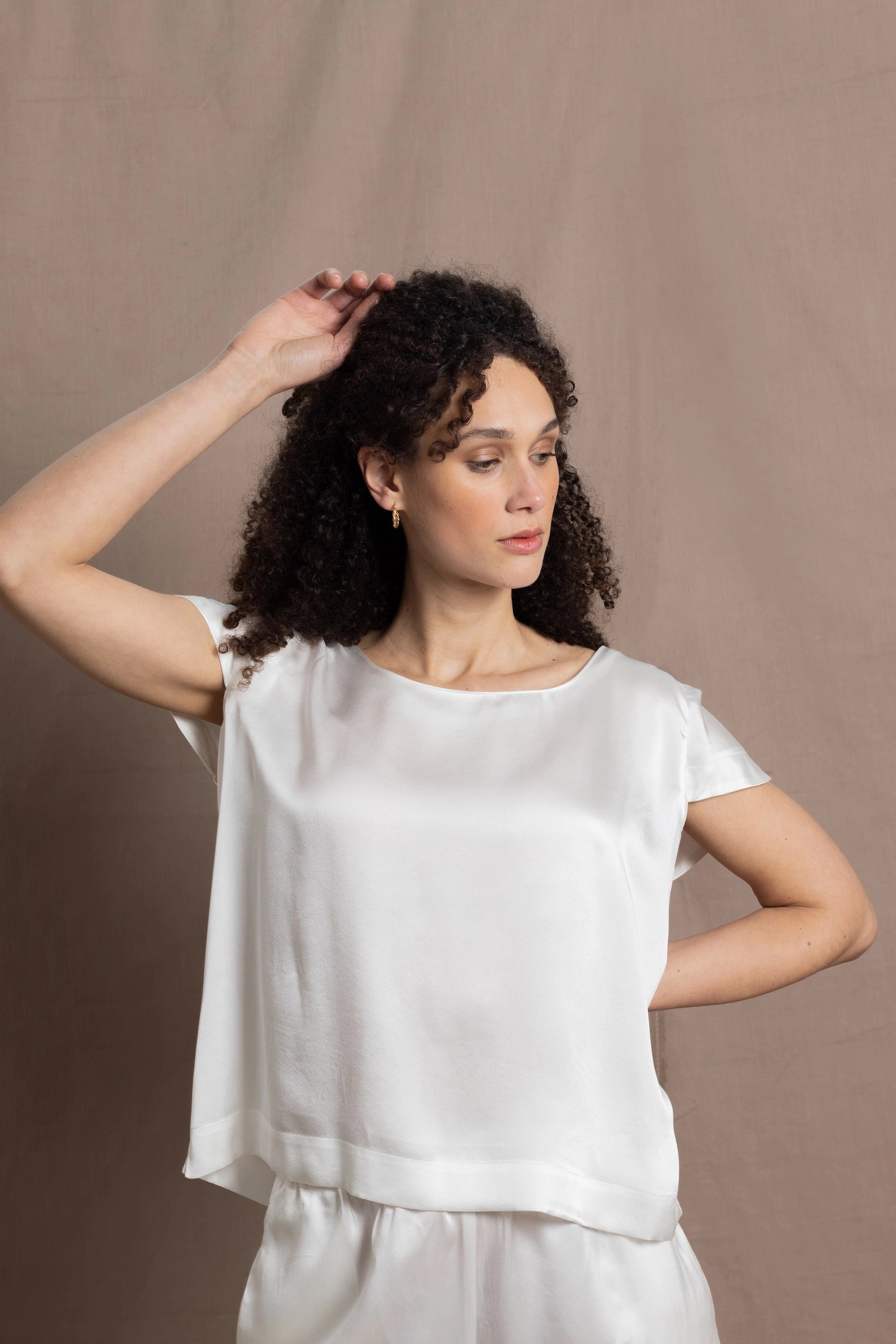 A lady wears a crew neck silk tshirt in white with butterfly sleeves