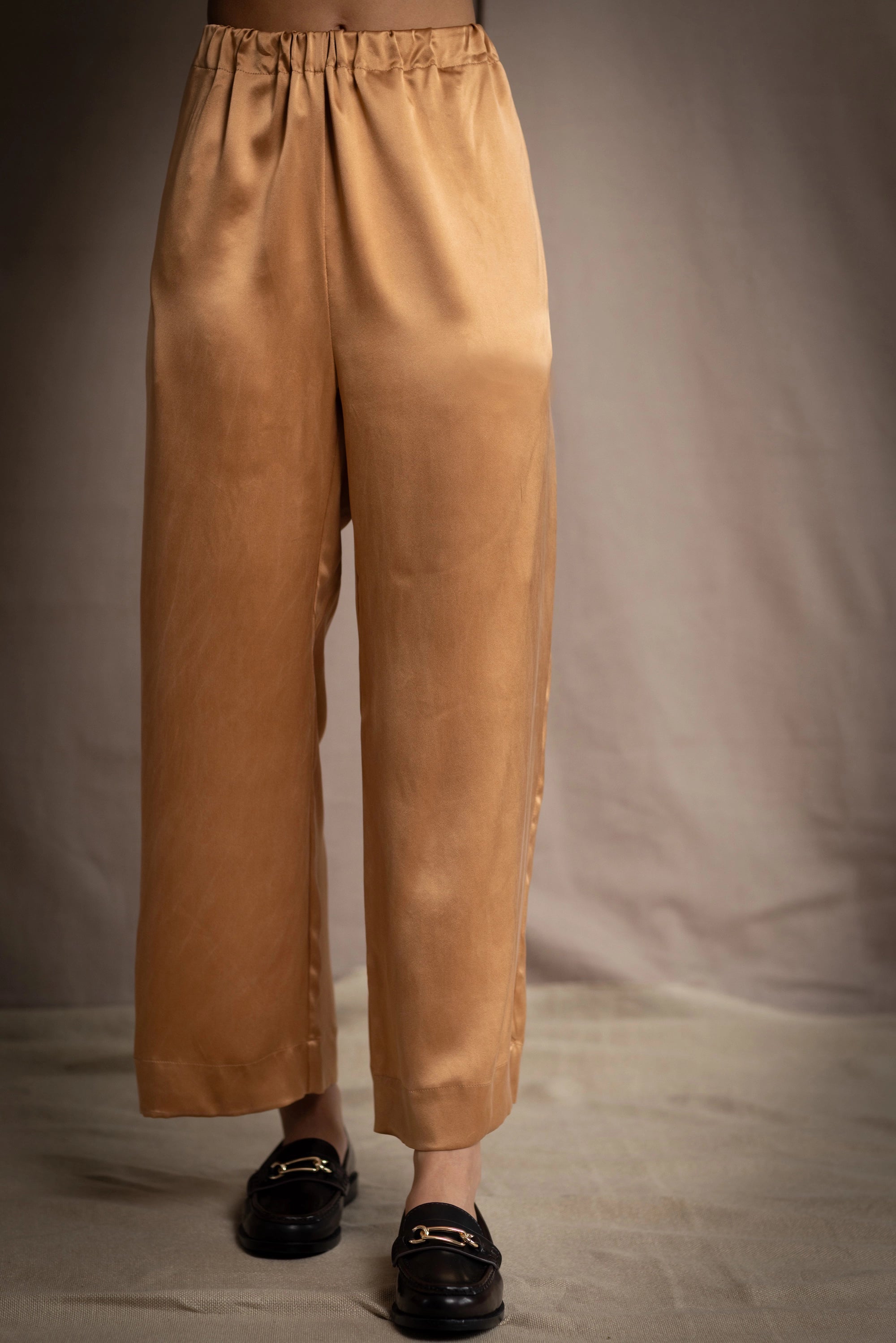 a woman wearing bronze silk pants with an elastic waist