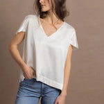 A woman wears a 100% silk v-neck t-shirt in white with a pair of jeans