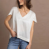 A woman wears a 100% silk v-neck t-shirt in white with a pair of jeans