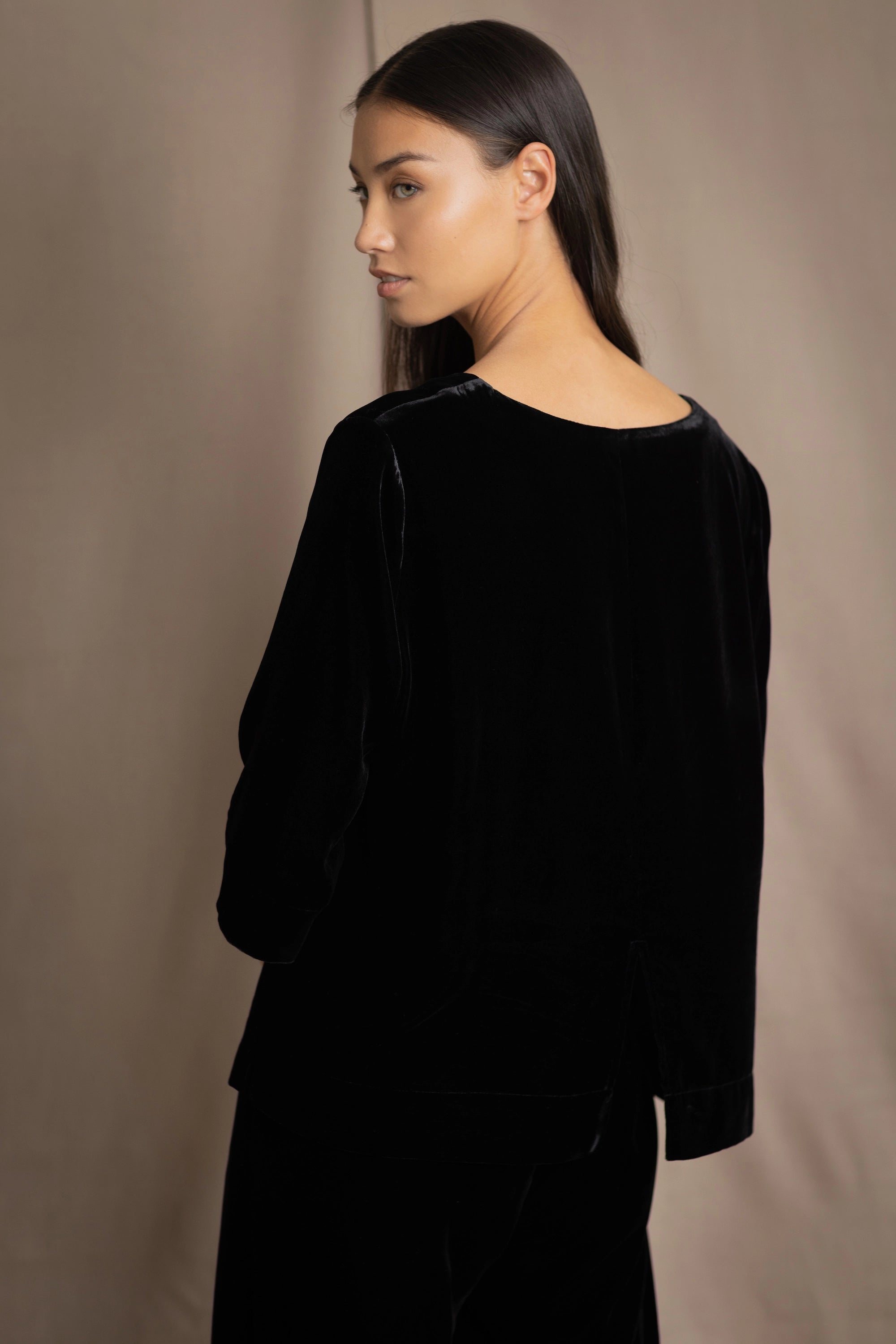 a woman wears a 3/4 sleeve silk velvet top in black with matching silk velvet trousers