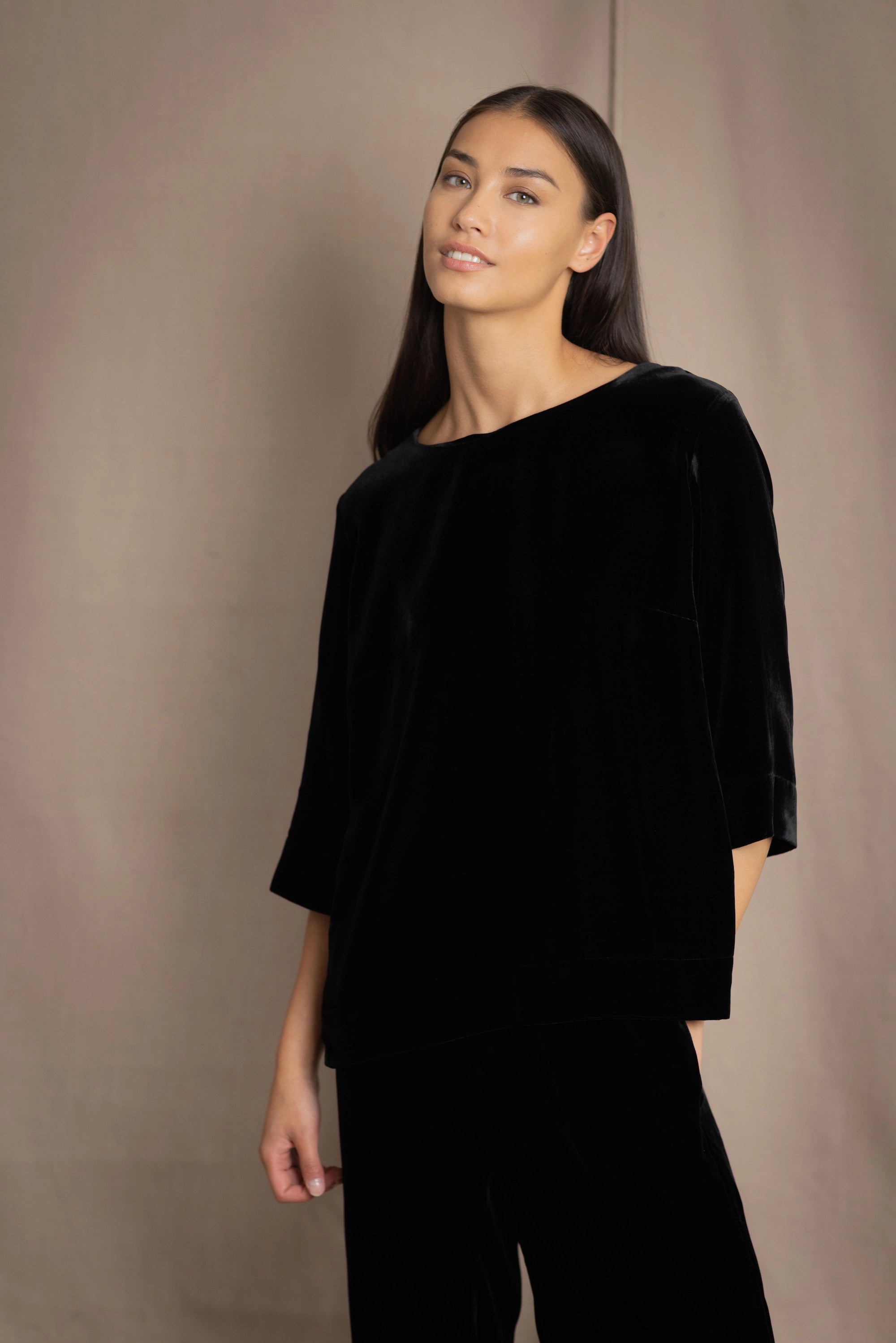 a woman wears a 3/4 sleeve silk velvet top in black with matching silk velvet trousers