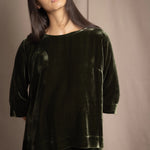 a woman wears a 3/4 sleeve top in silk velvet in olive green