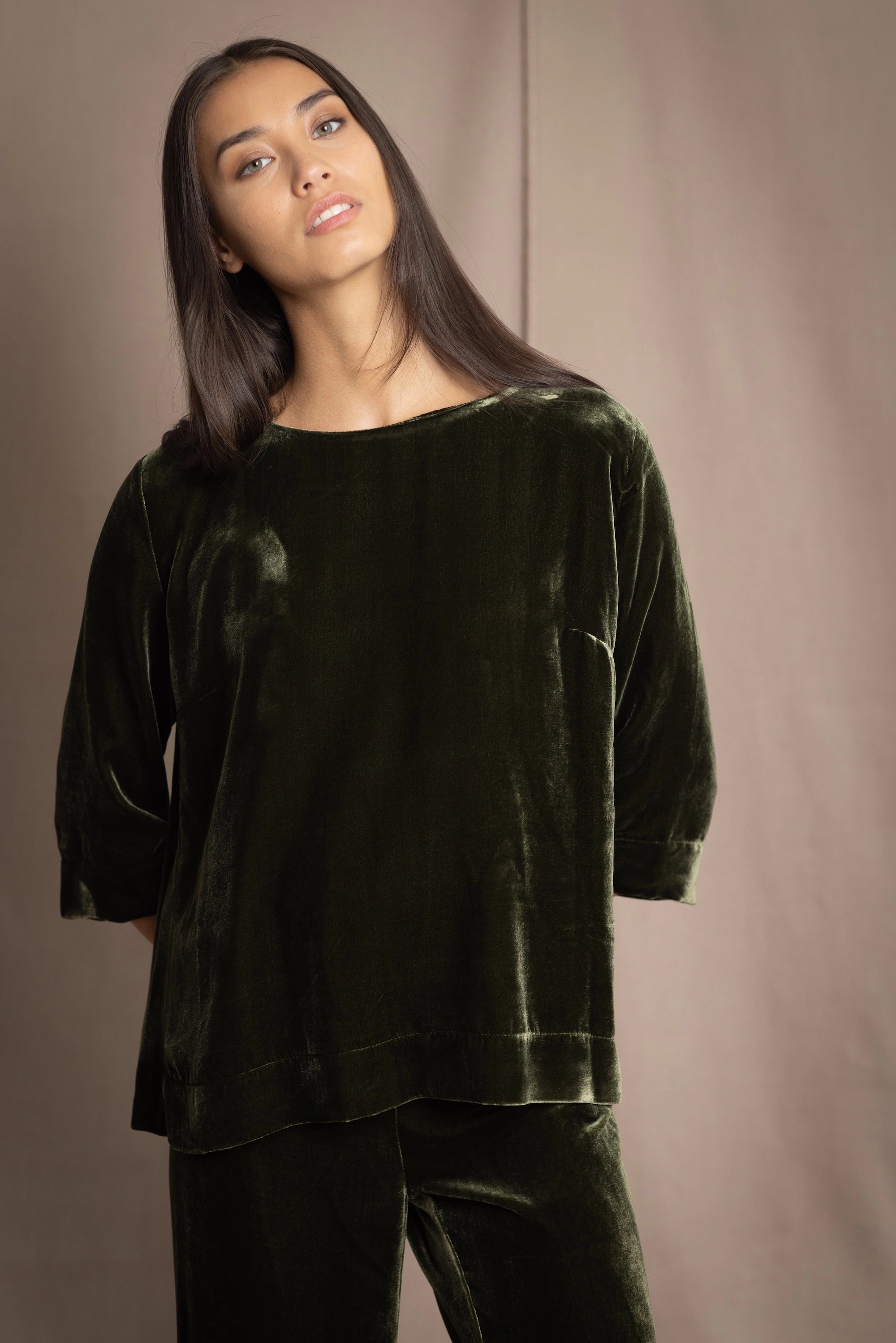 a woman wears a 3/4 sleeve top in silk velvet in olive green
