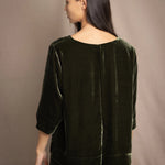 a woman wears a 3/4 sleeve top in silk velvet in olive green