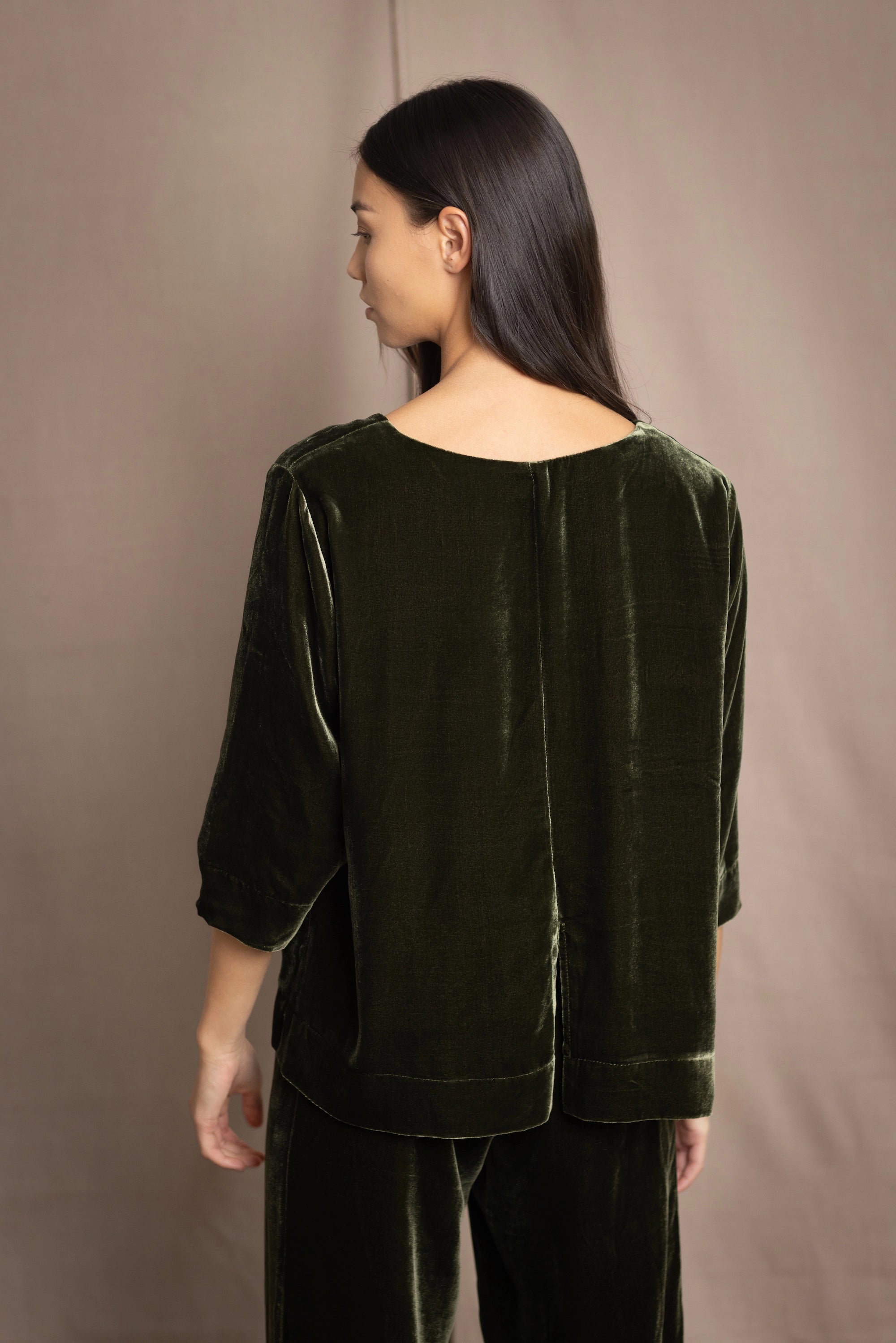 a woman wears a 3/4 sleeve top in silk velvet in olive green