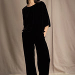 a woman wears a 3/4 sleeve silk velvet top in black with matching silk velvet trousers