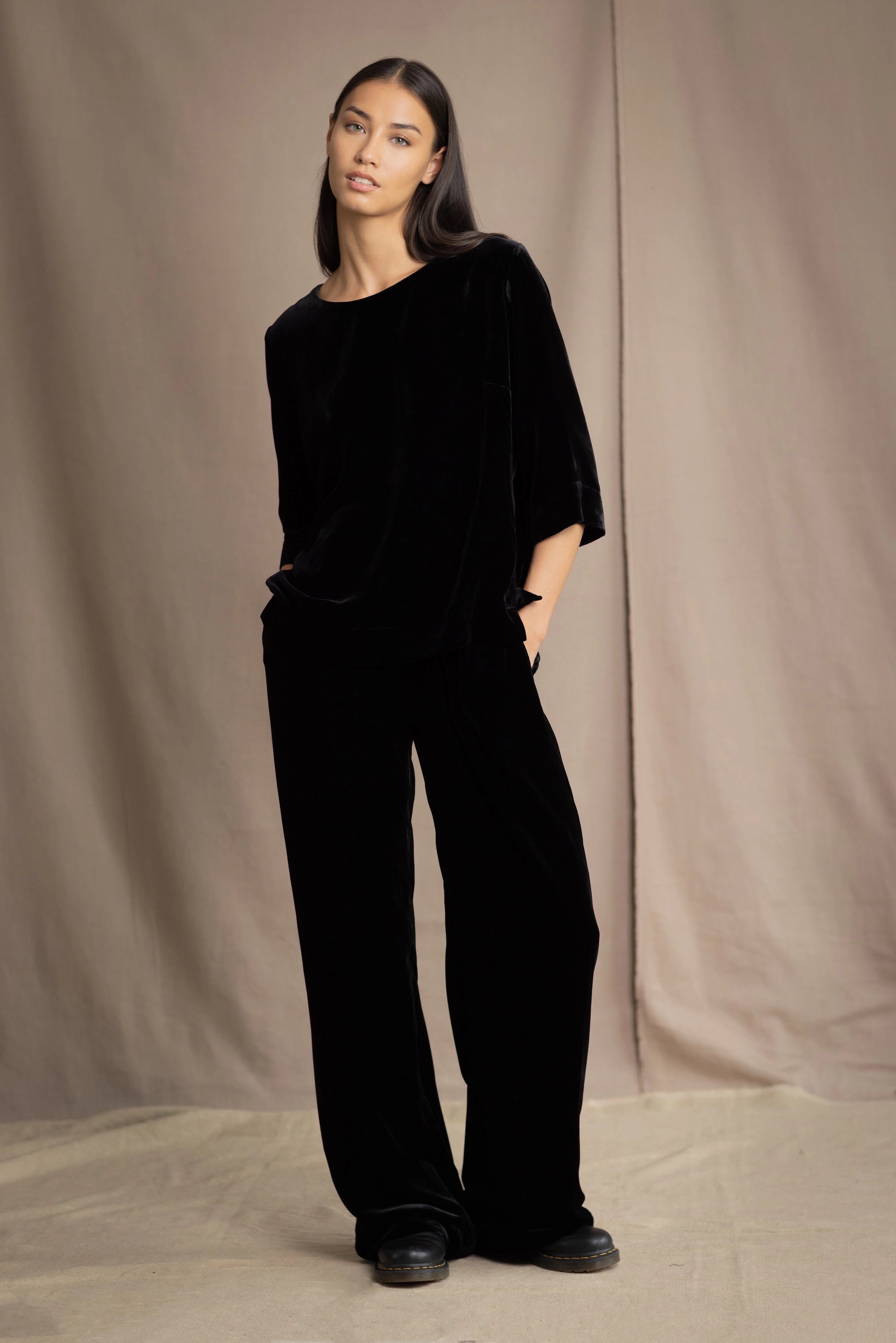 a woman wears a 3/4 sleeve silk velvet top in black with matching silk velvet trousers