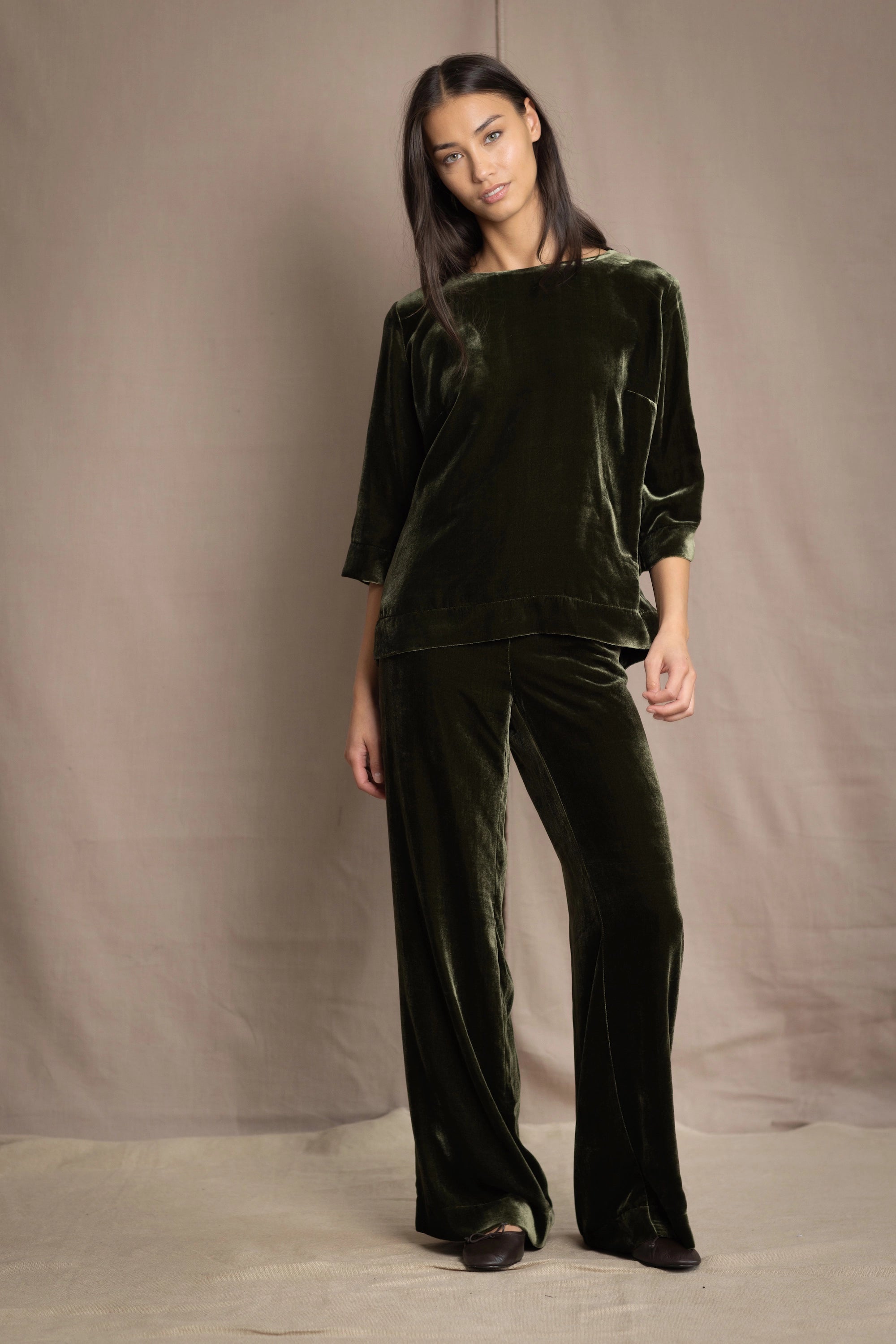 a woman wears silk velvet top and trousers in olive green