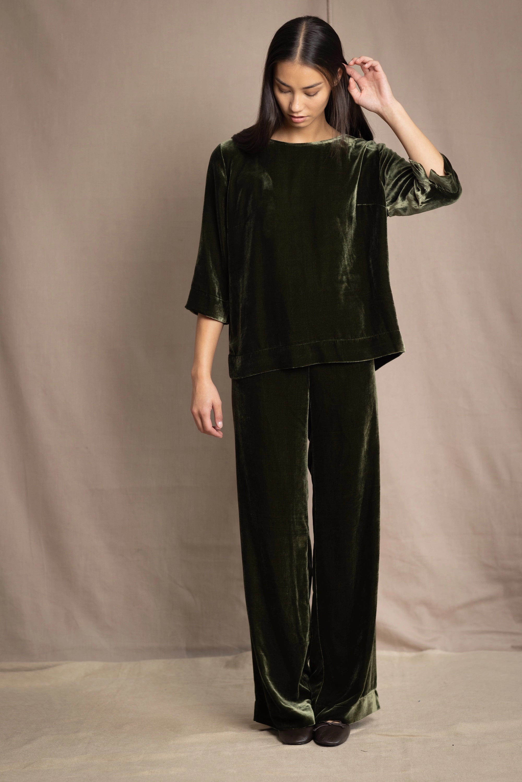 a woman wears a 3/4 sleeve top in silk velvet in olive green with silk velvet trousers