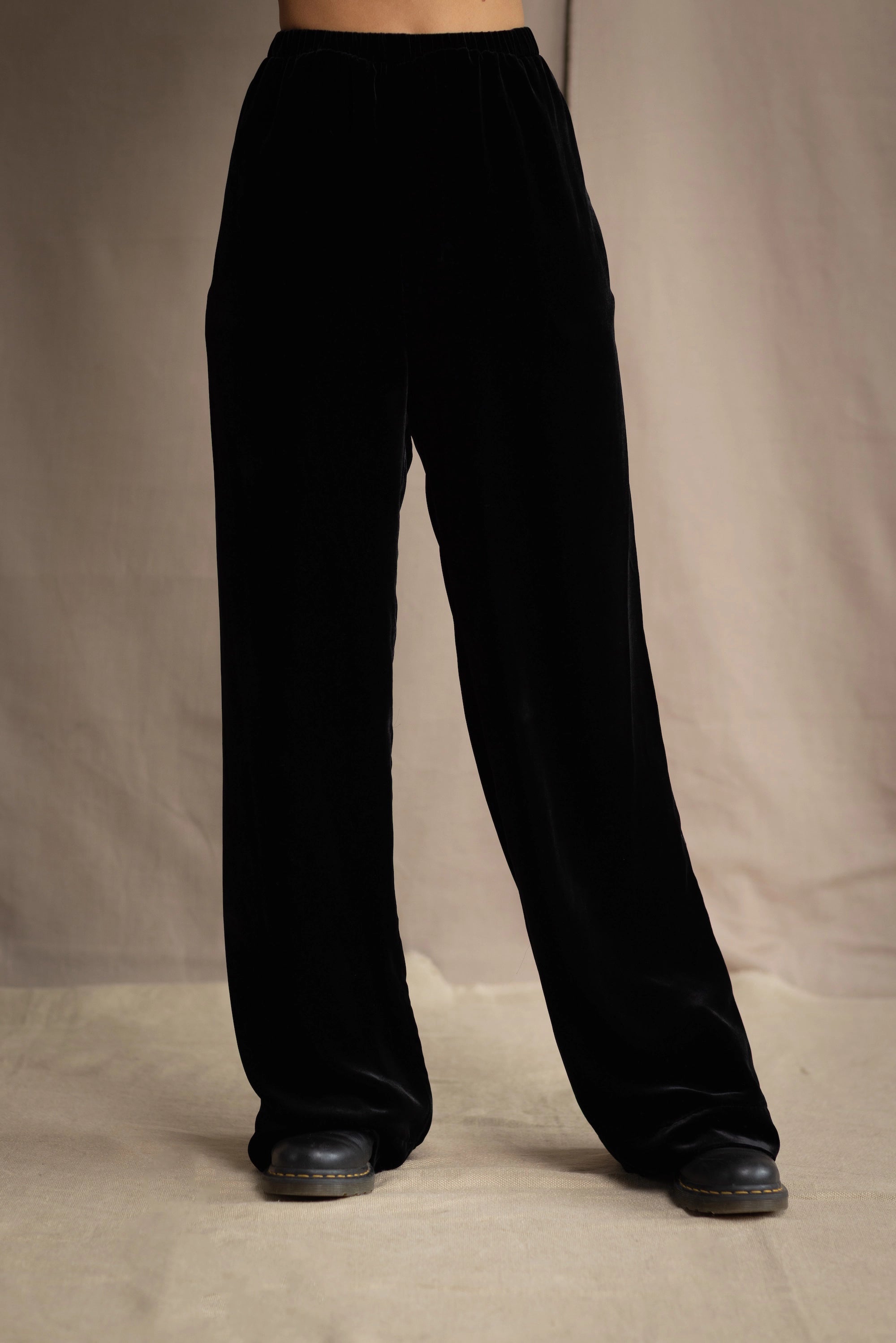 a woman wears silk velvet trousers in black with elasticated waist
