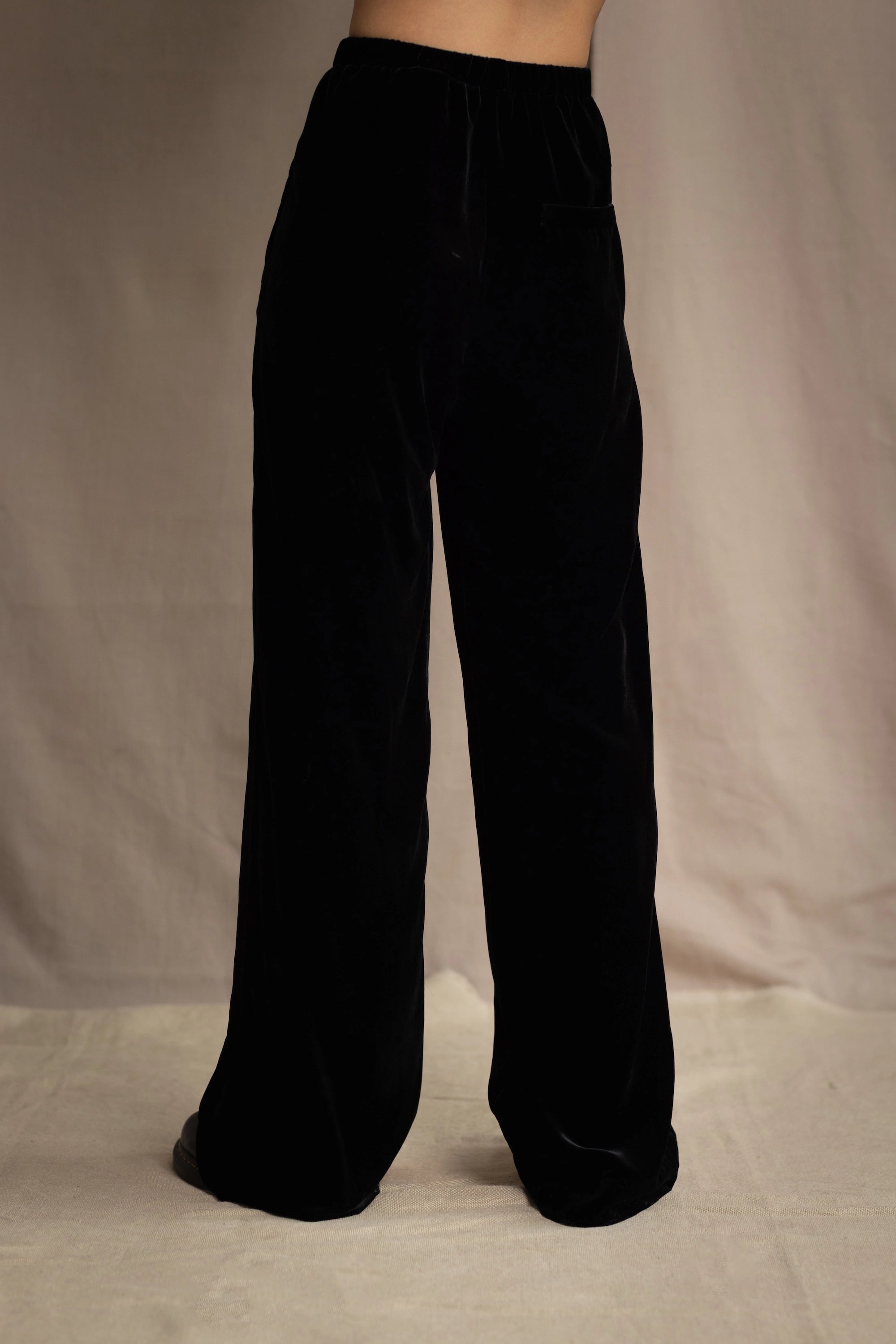 a woman wears silk velvet trousers in black with elasticated waist