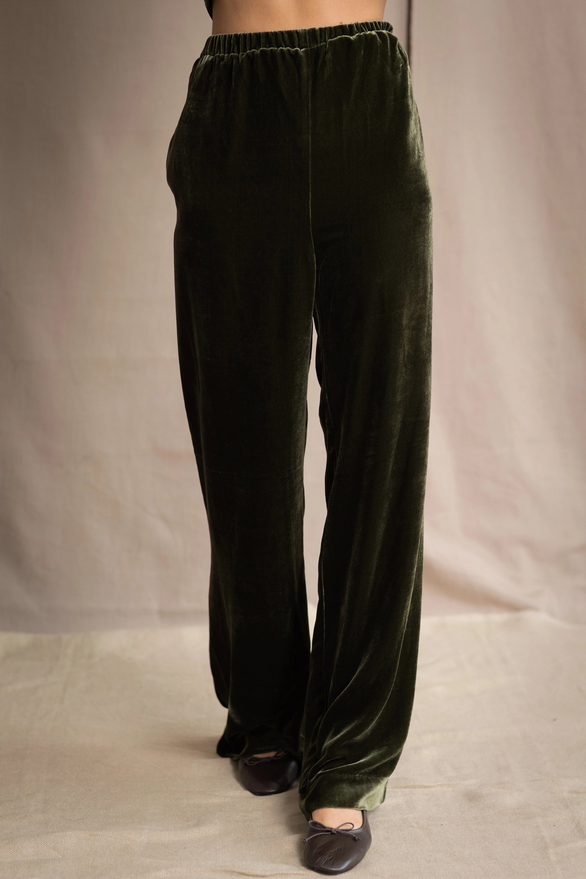 a woman wears silk velvet trousers in olive green with elastic waist
