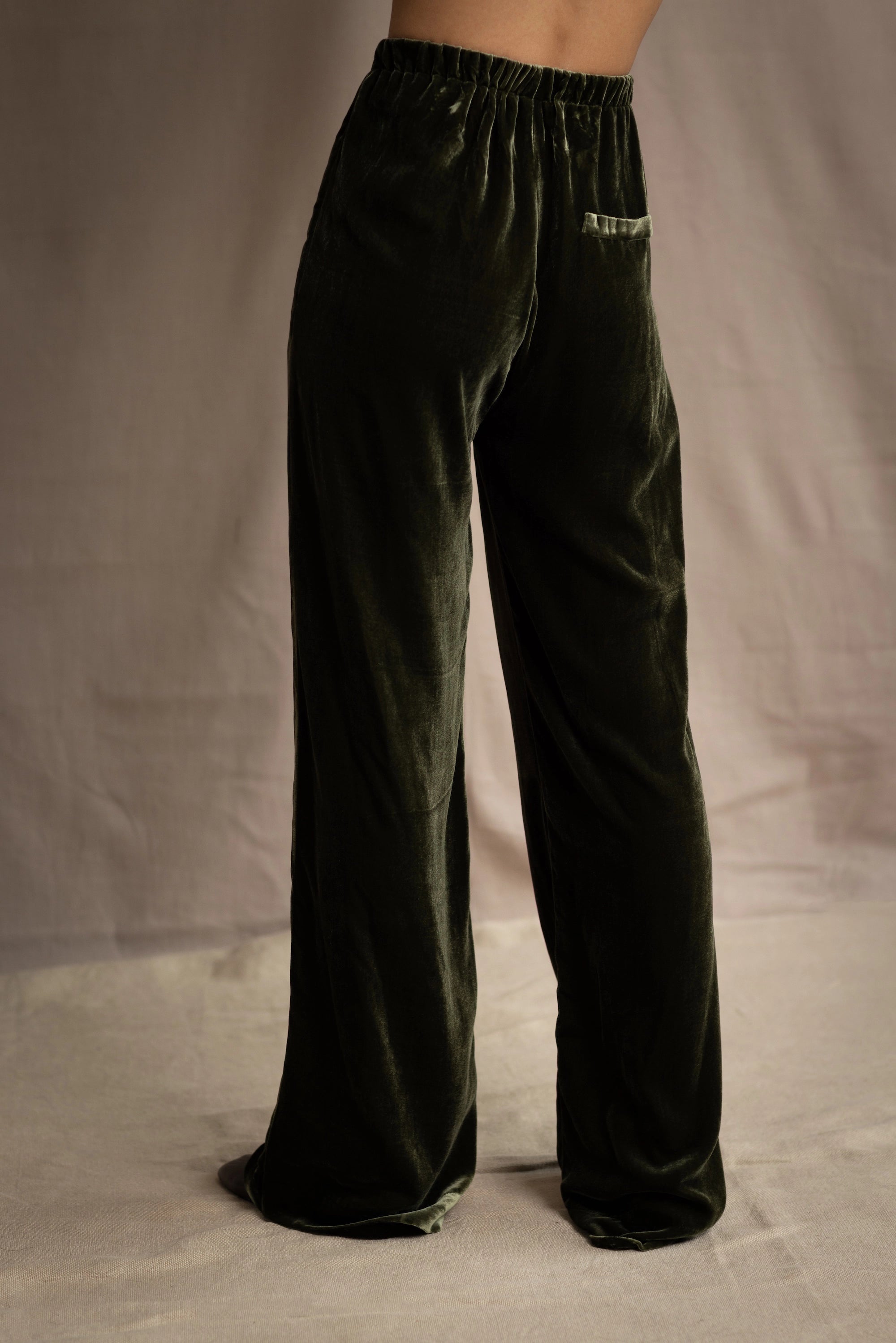 a woman wears silk velvet trousers in olive green with elastic waist