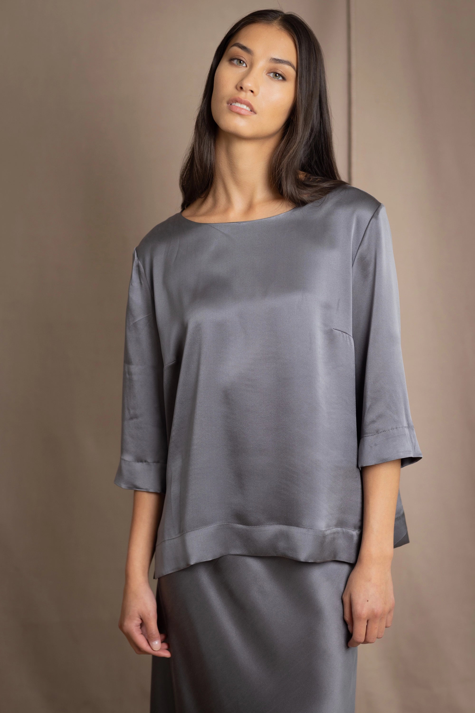 woman wearing a dark grey pewter silk 3/4 sleeve top blouse with matching silk skirt