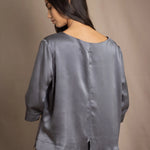 woman wearing a dark grey pewter silk 3/4 sleeve top blouse with matching silk skirt