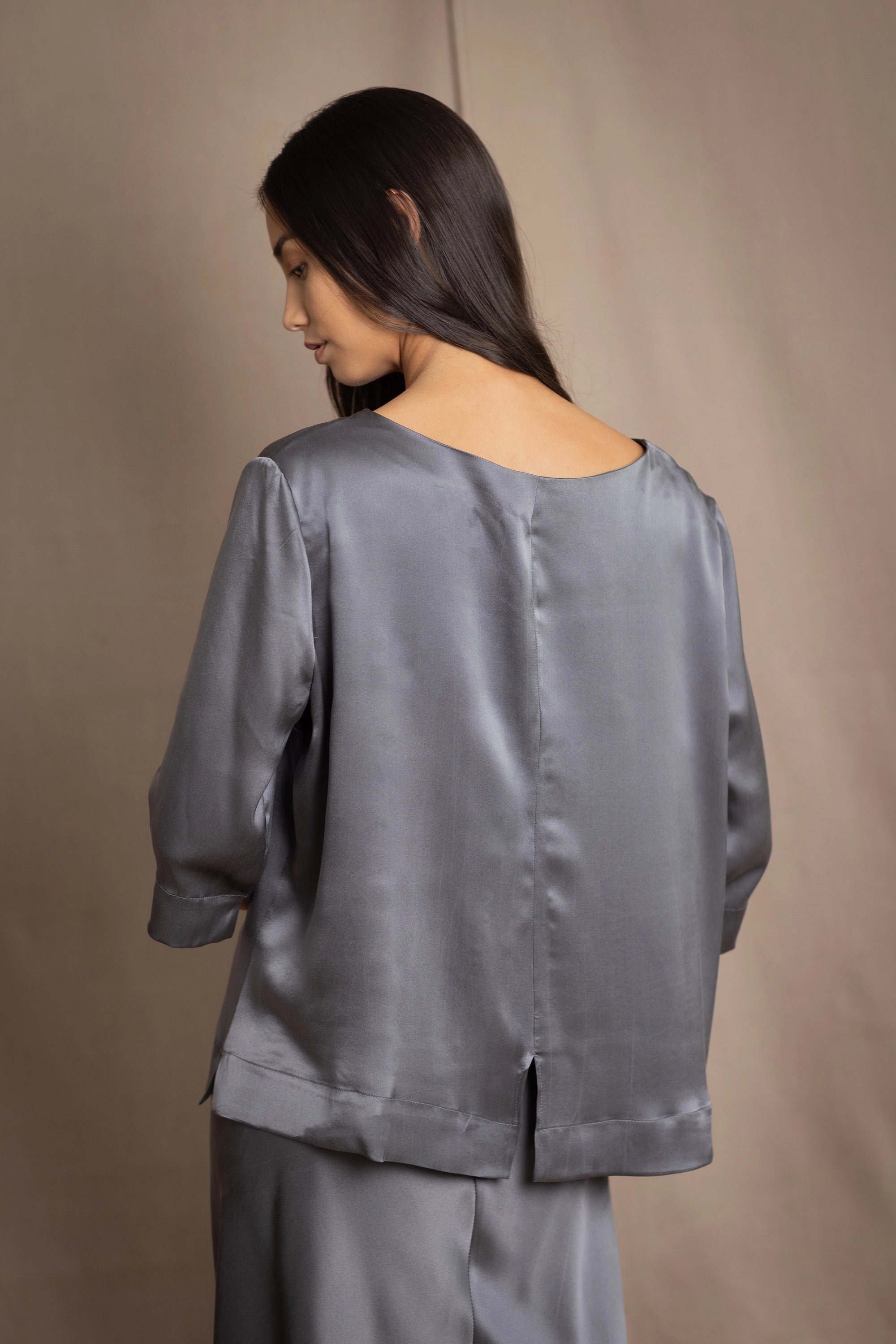 woman wearing a dark grey pewter silk 3/4 sleeve top blouse with matching silk skirt