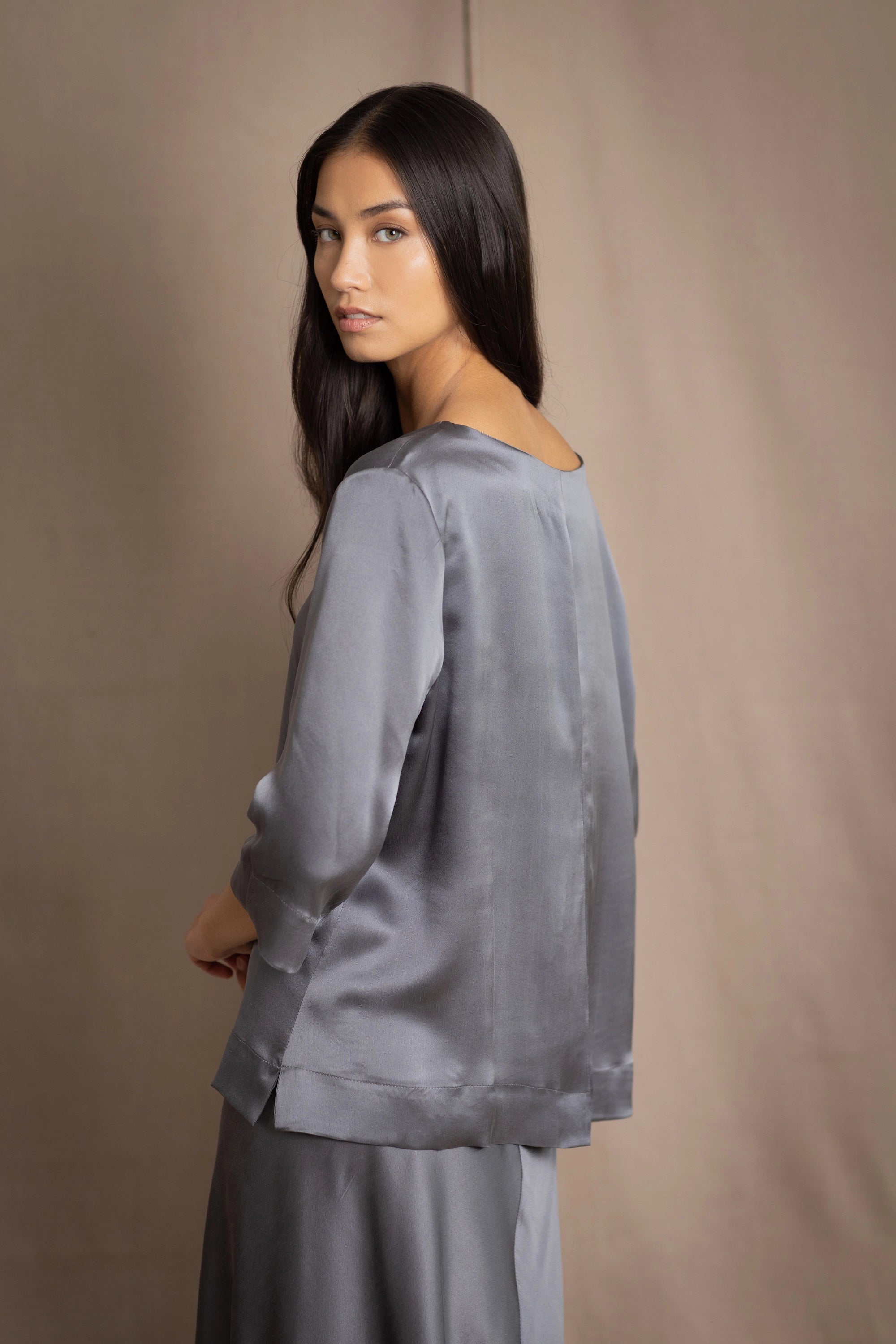 woman wearing a dark grey pewter silk 3/4 sleeve top blouse with matching silk skirt