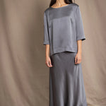 woman wearing a dark grey pewter silk 3/4 sleeve top blouse with matching silk skirt