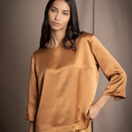 woman wearing a bronze silk 3/4 sleeve top blouse with matching silk trousers